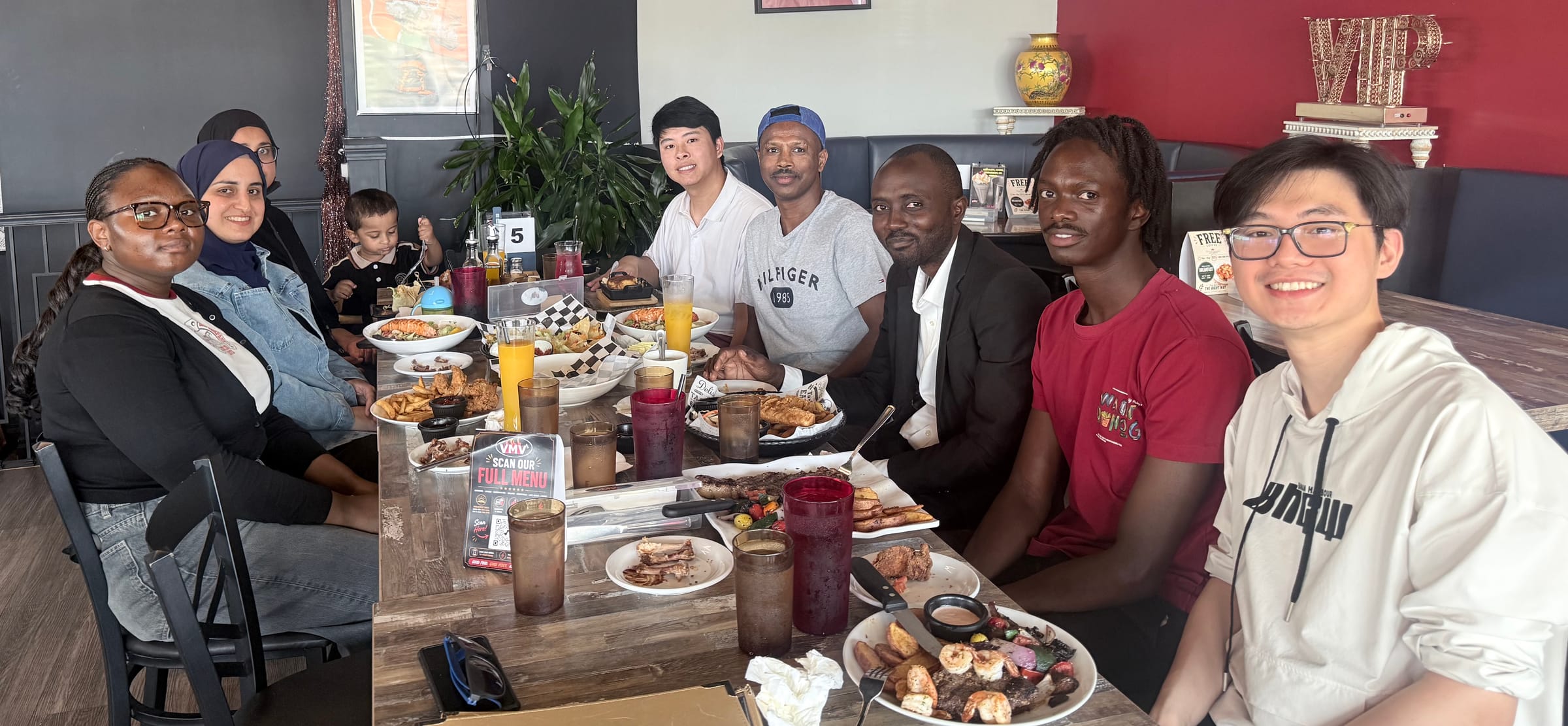 Members of the DIMMS Lab seated around a restaurant table, smiling at the camera